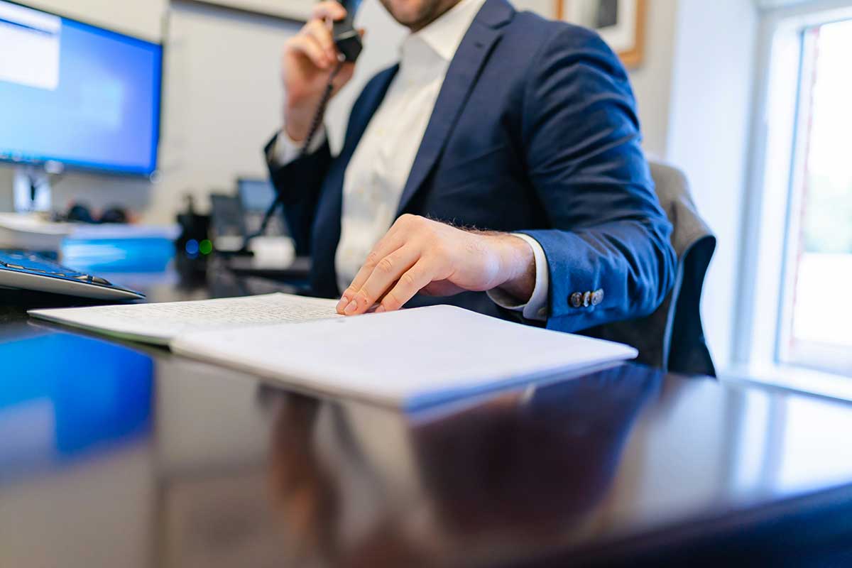 A Man Sitting At A Desk Writing On A Piece Of Paper