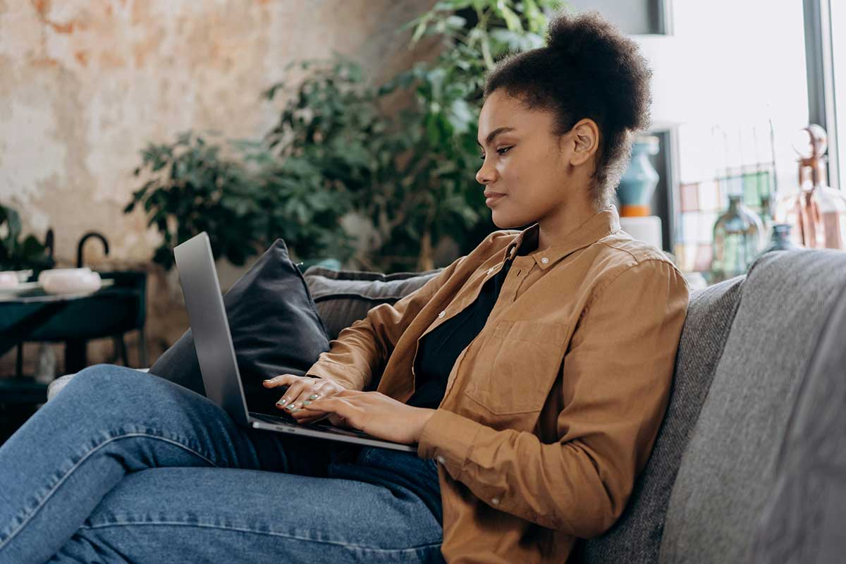 Woman On Sofa Looking At Laptop